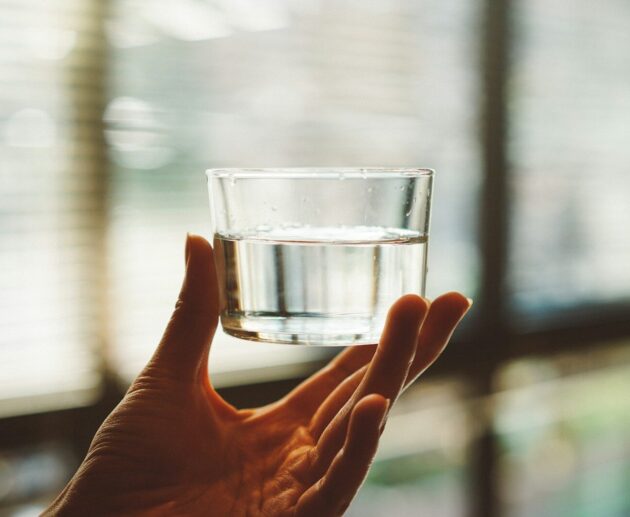 person holding clear glass cup with half-filled water