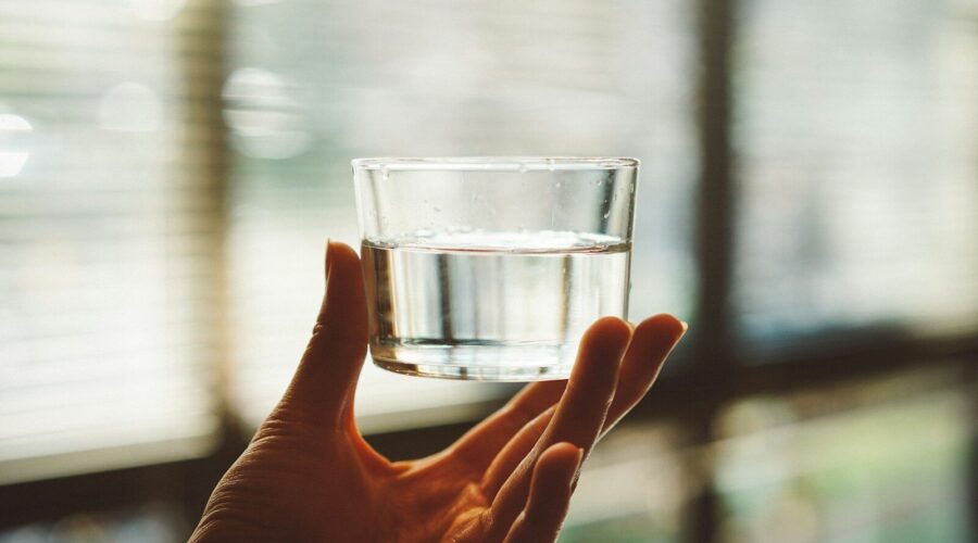 person holding clear glass cup with half-filled water