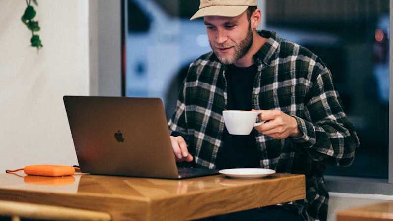 Man working on a laptop in a cafe, the public wifi situation where a free VPN for privacy matters most