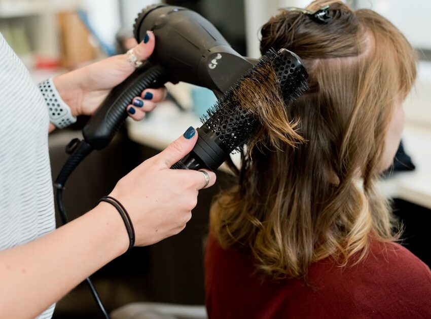 Hairstylist styling hair with a round hot air brush, the best hot air brush for styling smooth volume