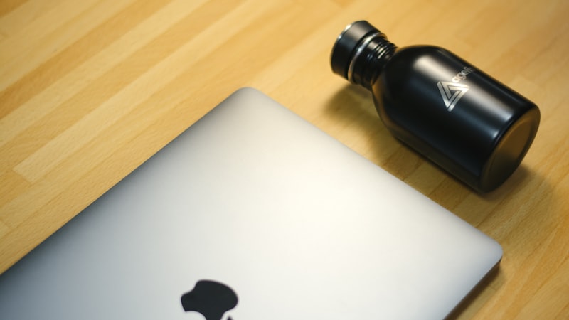 Reusable water bottle beside a laptop on a desk, where a water intake tracking bottle does most of its work
