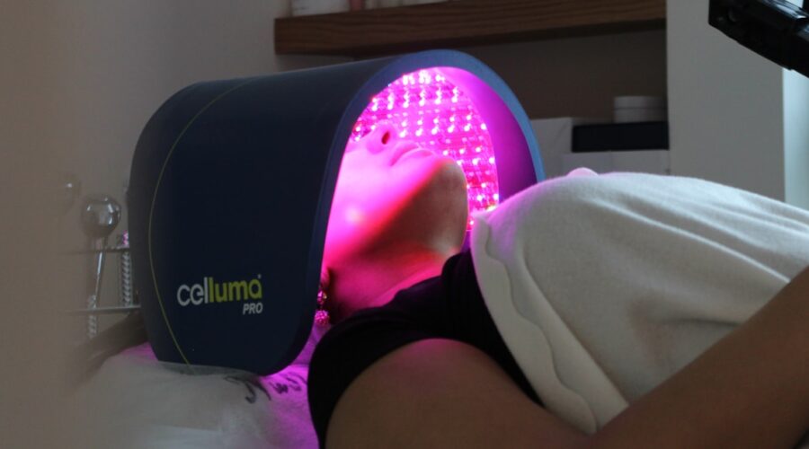 LED light therapy panel glowing over a face during treatment, the clinic version of an LED face mask for acne