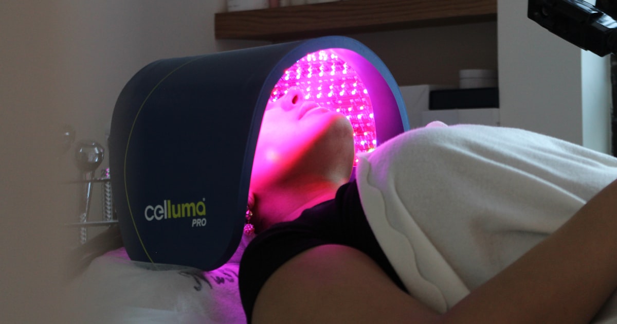LED light therapy panel glowing over a face during treatment, the clinic version of an LED face mask for acne
