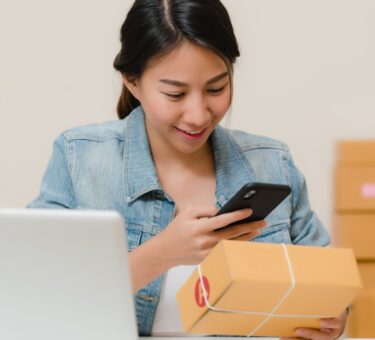 Online shop owner checking an order beside a laptop, the business deciding between Shopify vs WordPress AI e-commerce tools