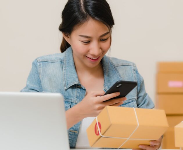 Online shop owner checking an order beside a laptop, the business deciding between Shopify vs WordPress AI e-commerce tools