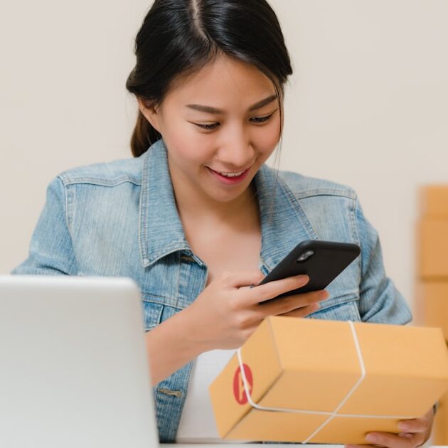Online shop owner checking an order beside a laptop, the business deciding between Shopify vs WordPress AI e-commerce tools