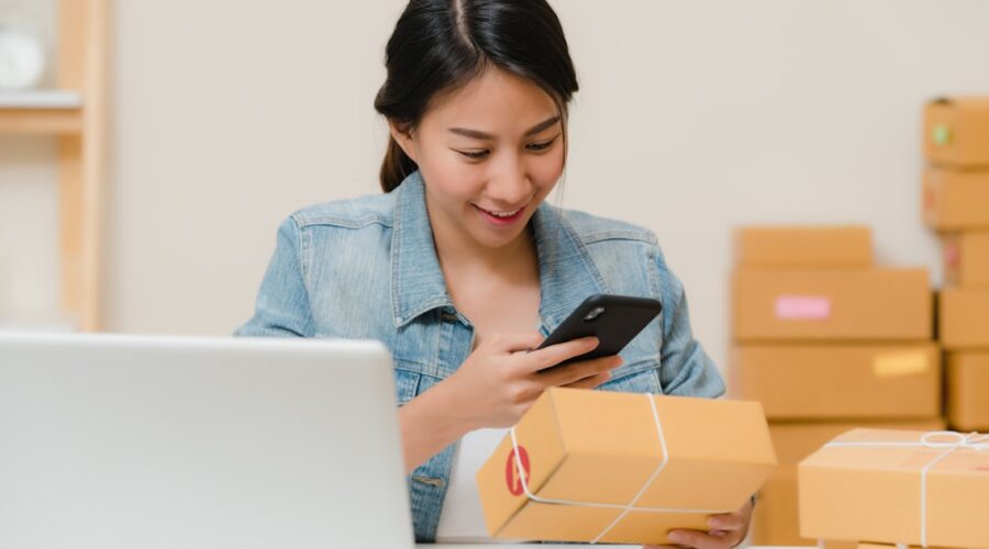 Online shop owner checking an order beside a laptop, the business deciding between Shopify vs WordPress AI e-commerce tools
