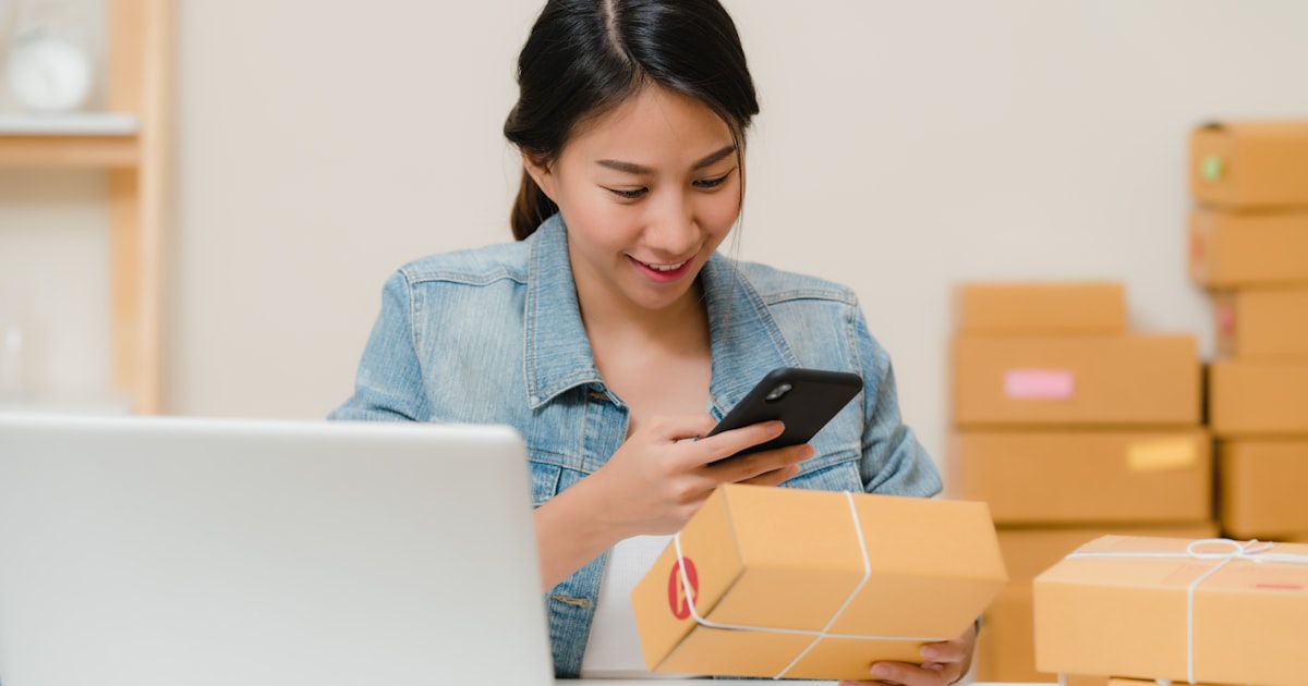 Online shop owner checking an order beside a laptop, the business deciding between Shopify vs WordPress AI e-commerce tools