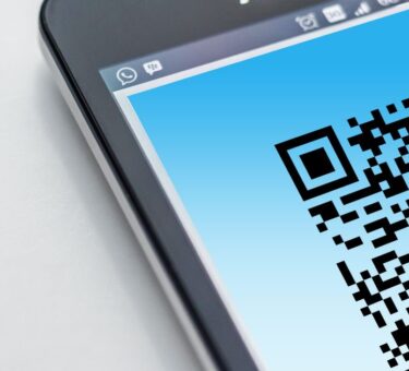 QR code filling a smartphone screen with its corner finder patterns visible, the two-dimensional side of the barcode scanner app vs QR comparison