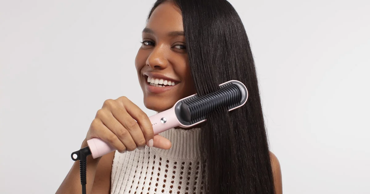 Woman running a heated styling tool through long hair, showing how the best hair straightening brush works in one pass