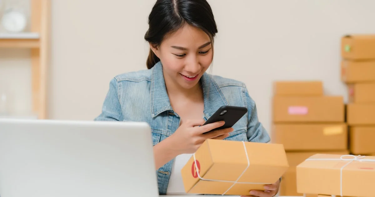 Online shop owner checking an order beside a laptop, the business deciding between Shopify vs WordPress AI e-commerce tools