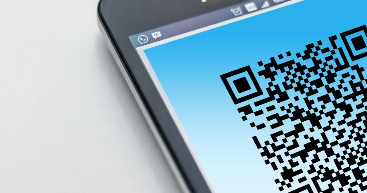 QR code filling a smartphone screen with its corner finder patterns visible, the two-dimensional side of the barcode scanner app vs QR comparison