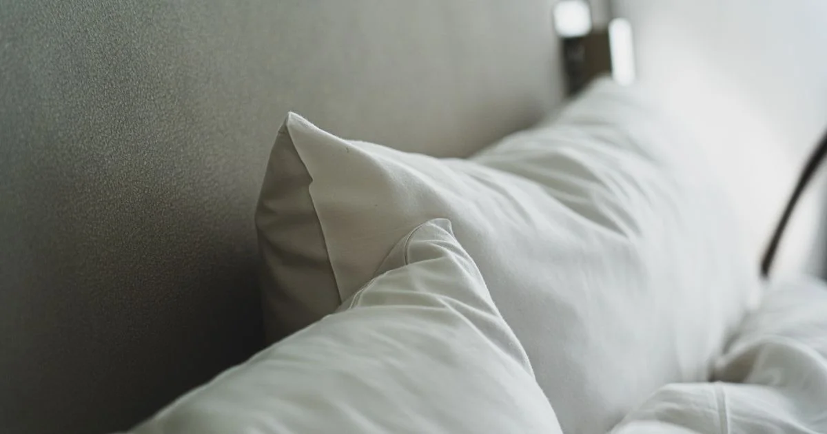 Crisp white bed pillows in cool morning light, the setup hot sleepers are trying to get right