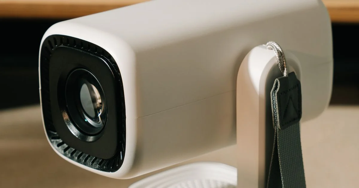 Close-up of a compact white portable mini projector on a stand, the kind used as a mini projector for home theater