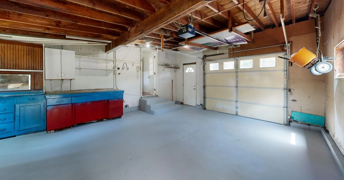 A residential garage with a ceiling-mounted opener and rail above a sectional door, the hardware behind a Chamberlain MyQ vs Genie smart opener decision