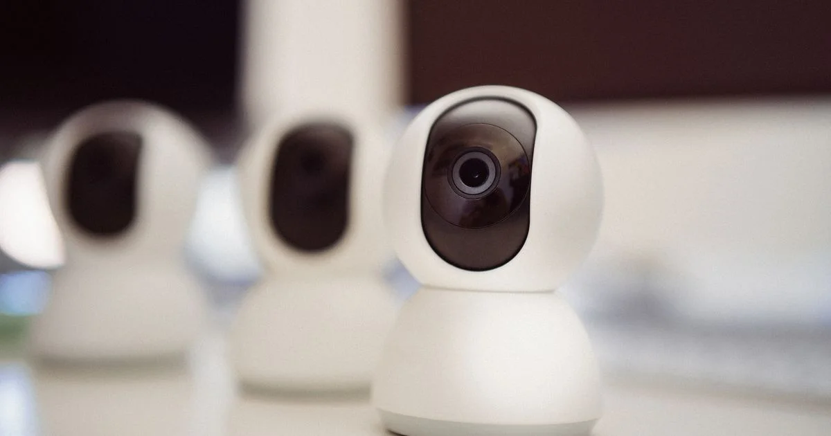 Three white home security cameras lined up on a table, the kind used in a top rated home security camera system