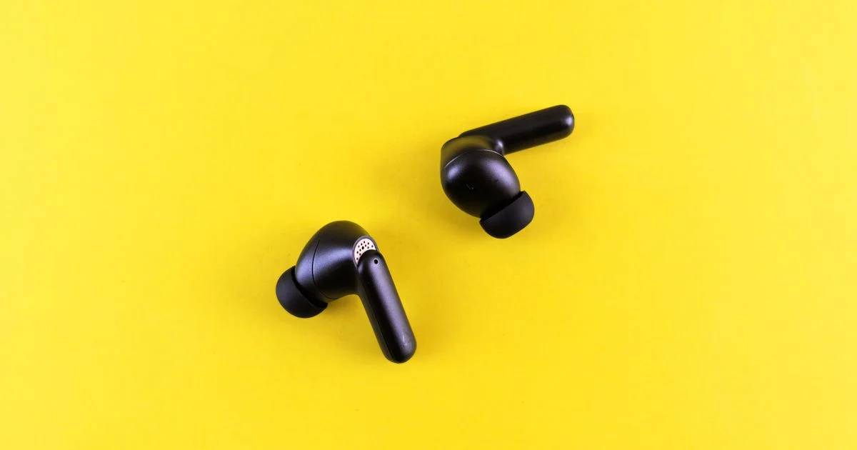 Black noise cancelling earbuds for commuting with silicone ear tips and a feedforward microphone vent on the stem