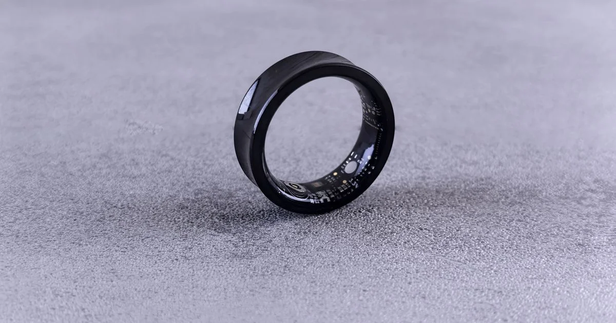 Smart ring standing on edge with its internal optical sensors visible, the ring side of the oura ring or whoop band which is better question