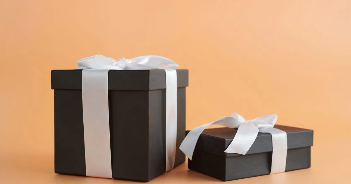 Two plain black gift boxes tied with white ribbon, the ready made side of Personalized vs Ready Made Gifts