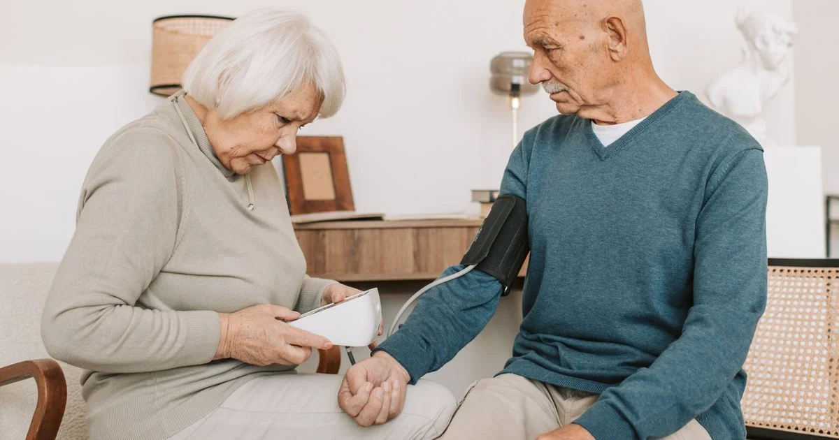 Older couple at home using a digital blood pressure monitor, one of the best remote patient monitoring devices