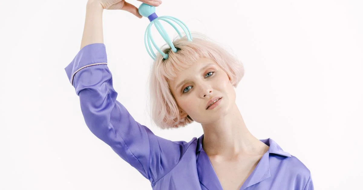 Woman using a handheld scalp massager device on the top of her head