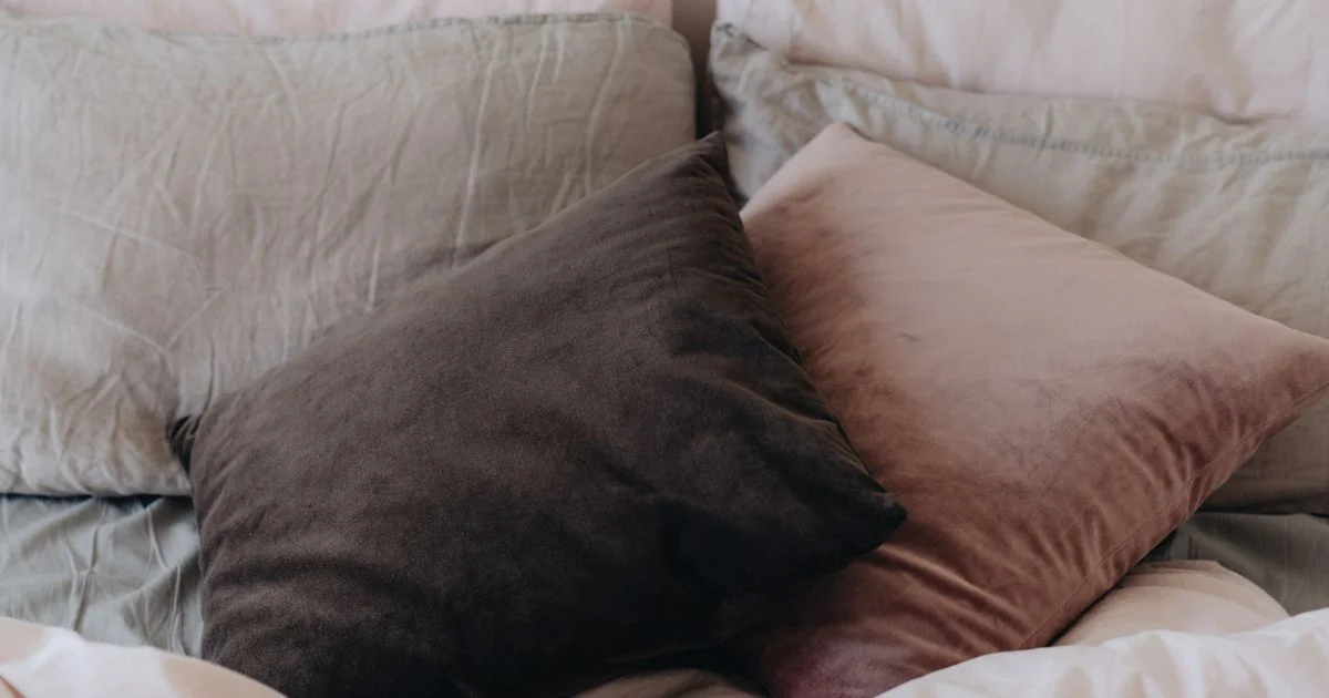 Bed pillows and cushions resting on an unmade bed, the ordinary side of the smart anti-snoring pillow vs regular pillow comparison