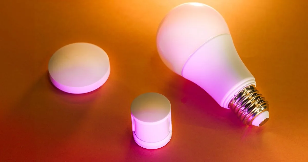 A color-changing smart LED bulb beside a motion sensor and hub, core hardware for the best smart lights for home automation