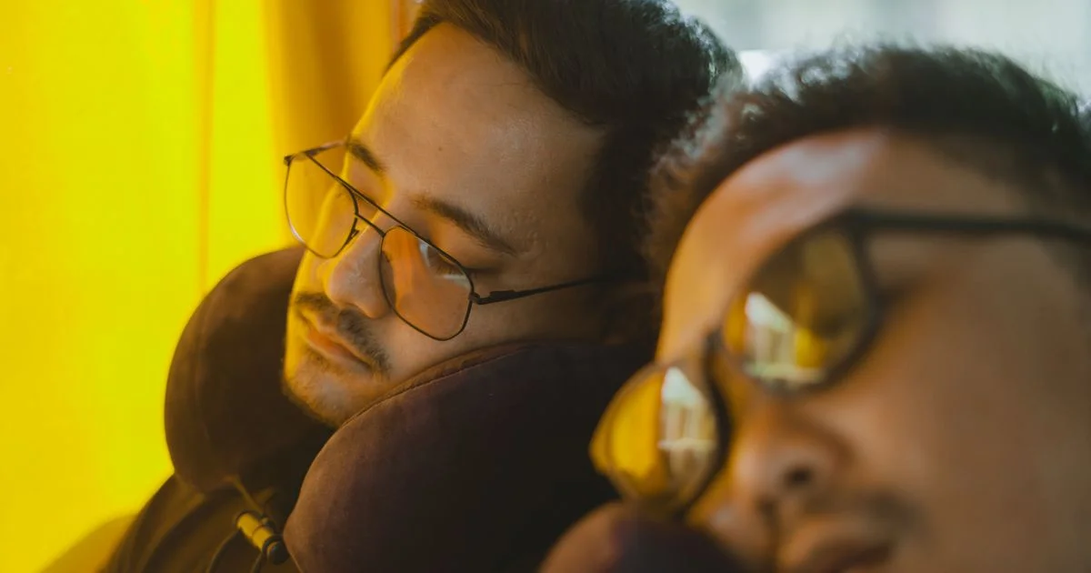 Two passengers asleep on a bus wearing horseshoe supports, the everyday test behind travel pillow vs neck pillow