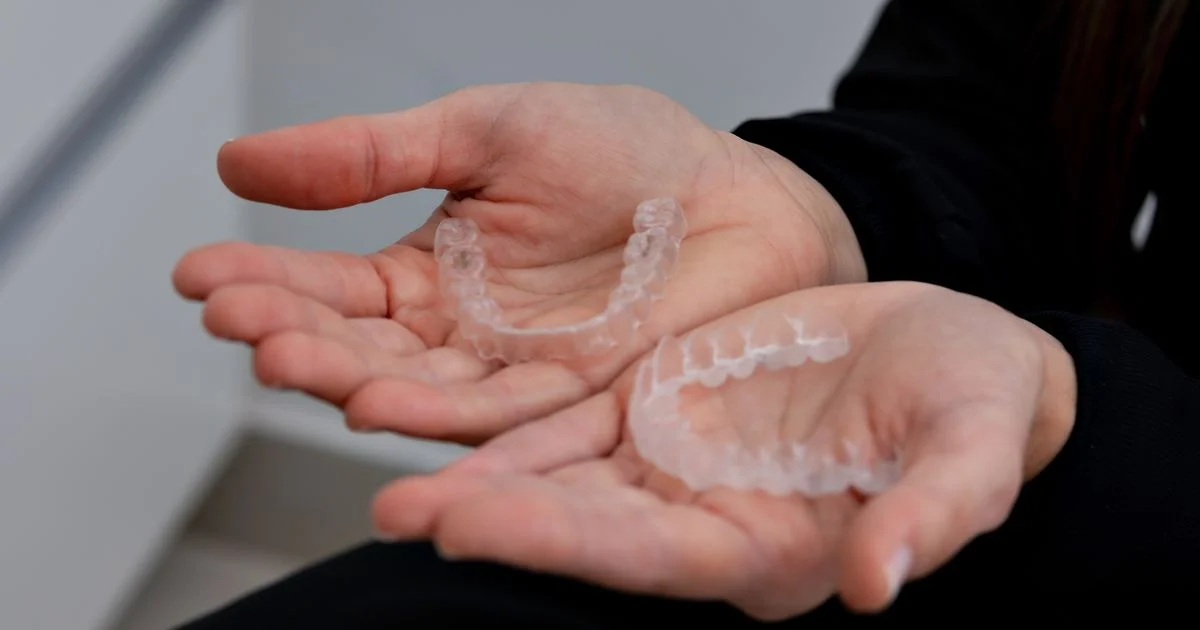 Two clear thermoplastic retainers held in open palms, the appliance ultrasonic retainer cleaners are made for