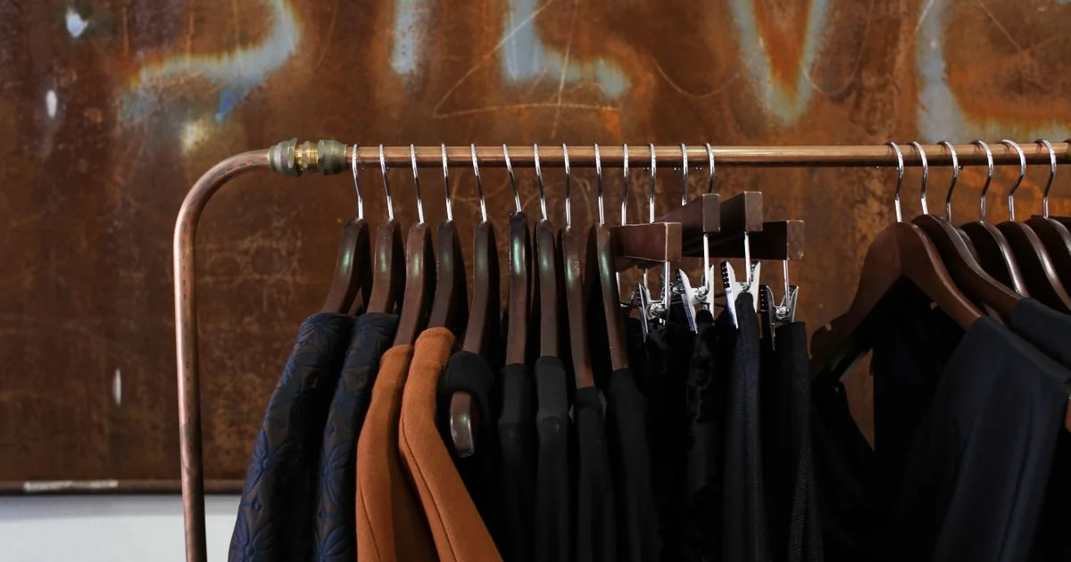 A retail rail of garments on wooden hangers, the point at which the Activewear vs athleisure label gets assigned