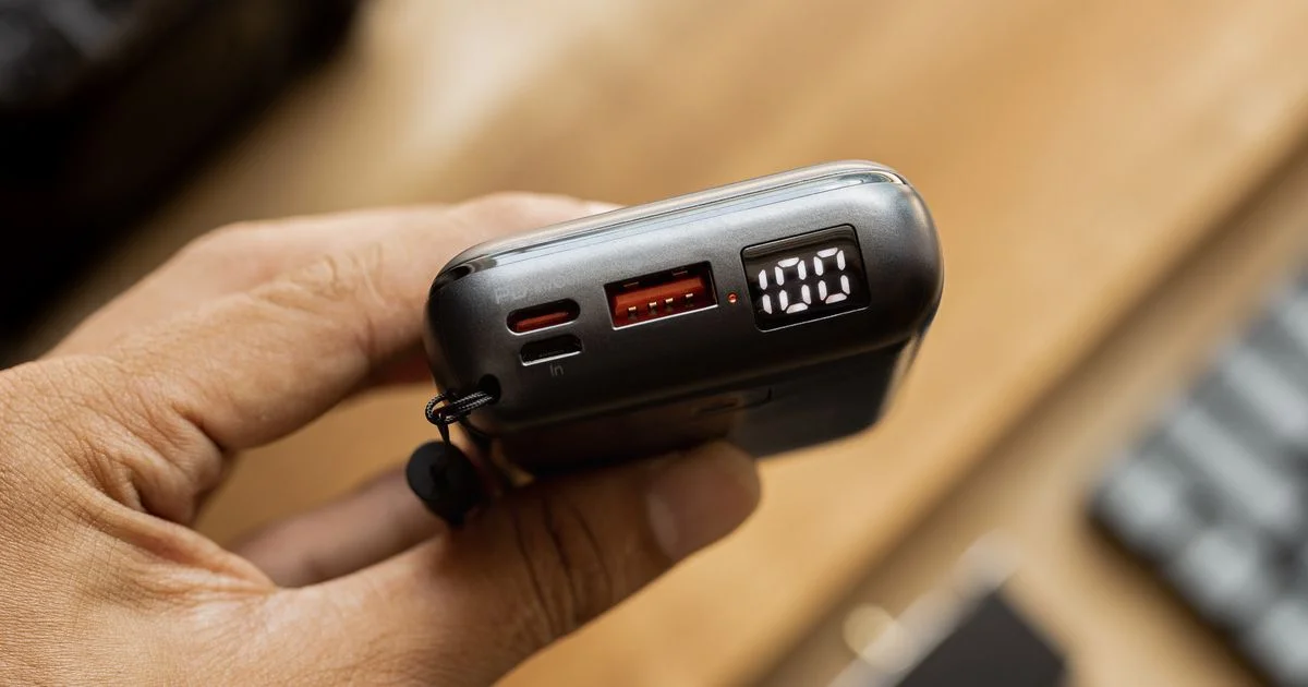 A compact power bank held in one hand with its USB-C port, USB-A port and charge display visible, the port face at issue in the anker vs belkin power bank comparison