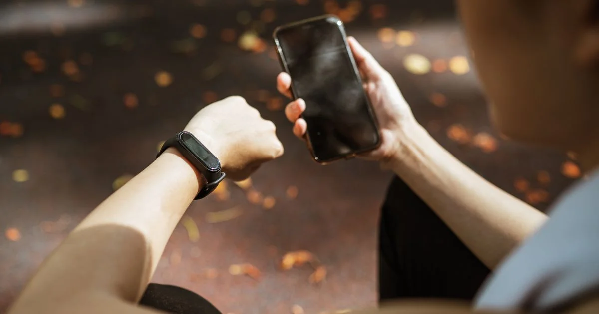 A wrist tracker worn beside a phone held in the other hand, the pairing that settles the Apple Watch vs Samsung Galaxy Watch choice